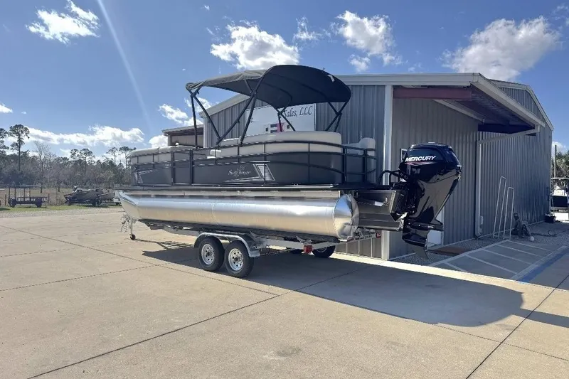 Slide: The Image of 2026 SunChaser Vista LR DH pontoon boat on trailer, parked outside a metal building. - 7