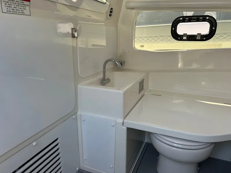 Slide: The Image of Interior of a modern boat cabin with a sink and toilet, bright walls, and a small window. - 25