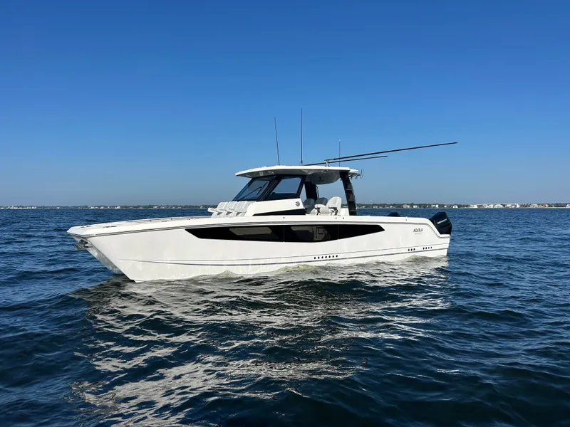 Slide: The Image of A modern Aquila A36MC boat from 2027 on calm waters under a clear sky. - 1