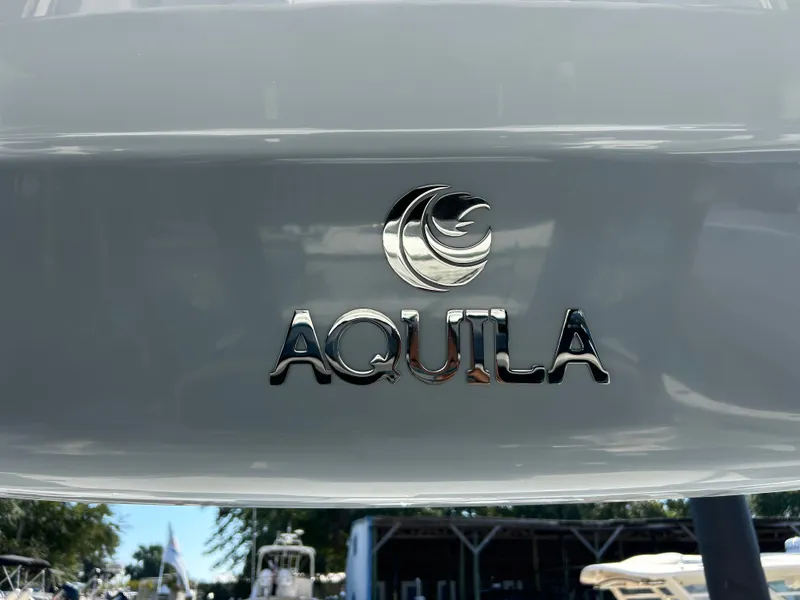 Slide: The Image of Close-up of the Aquila logo on a boat hull, with other boats in the background. - 34