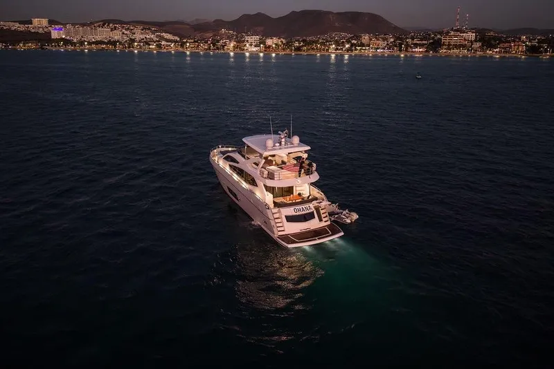 Slide: The Image of Luxurious 2012 Sunseeker Manhattan 73 yacht illuminated at night near a coastal city. - 10