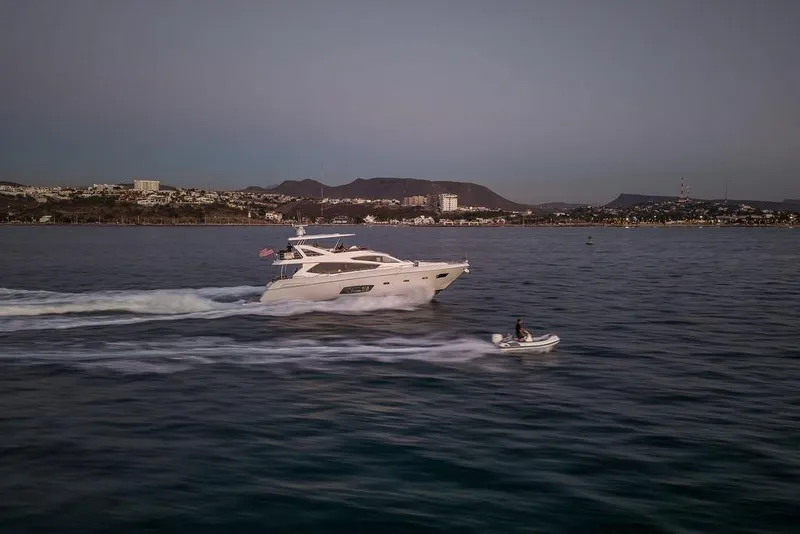 Slide: The Image of 2012 Sunseeker Manhattan 73 yacht cruising with jet ski nearby at sunset. - 11