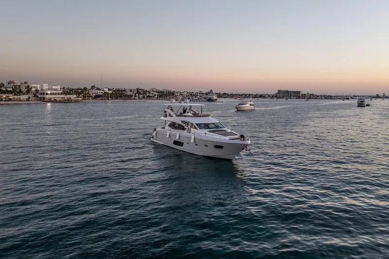 Slide: The Image of Luxurious 2012 Sunseeker Manhattan 73 yacht cruising at sunset near a coastal city. - 13