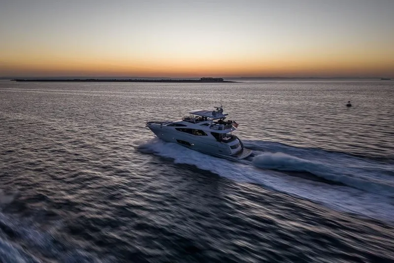 Slide: The Image of Luxurious 2012 Sunseeker Manhattan 73 yacht cruising at sunset on open water. - 2