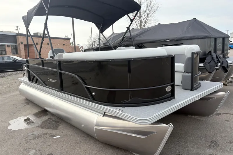 The Image of 2026 Crest 200SE pontoon boat with black exterior and canopy, parked outdoors. - 0
