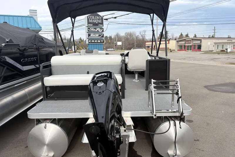 Slide: The Image of 2026 Crest 200SE pontoon boat with outboard motor and seating, displayed at a marina. - 1