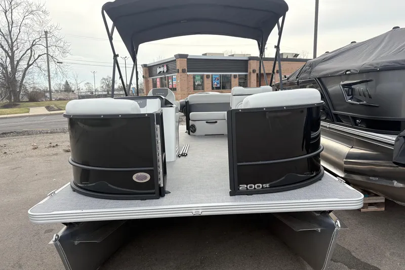 Slide: The Image of 2026 Crest 200SE pontoon boat with black exterior and canopy, parked outdoors. - 11