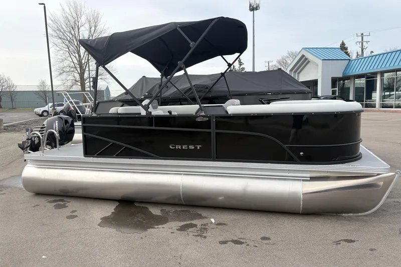 Slide: The Image of 2026 Crest 200SE pontoon boat with black canopy, parked outdoors. - 3