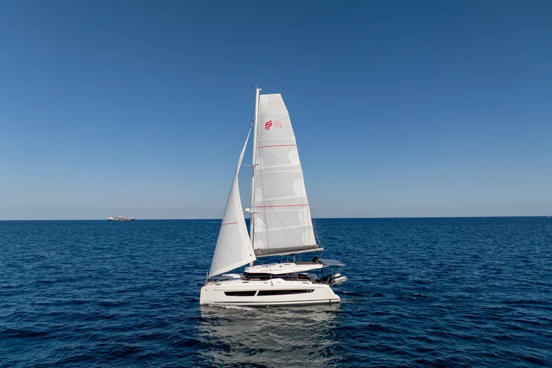 The Image of 2025 Fountaine Pajot FP41 Catamaran sailing on open sea under clear blue sky. - 0