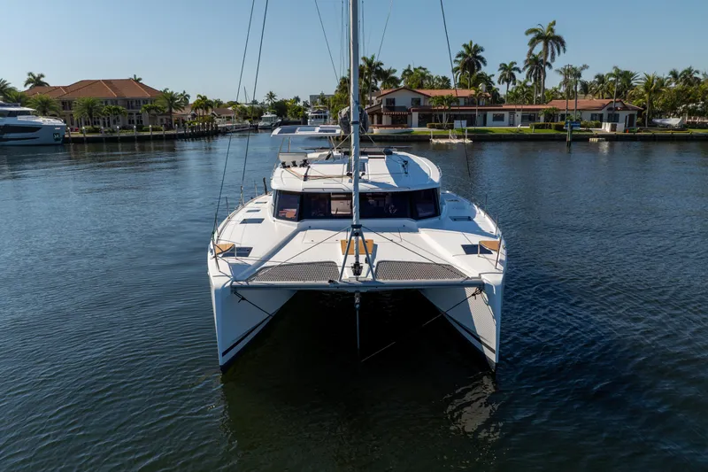 Slide: The Image of 2025 Fountaine Pajot FP41 Catamaran on calm water, surrounded by palm trees and waterfront homes. - 10