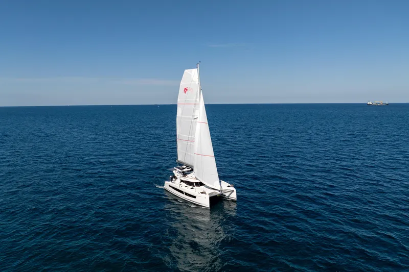 Slide: The Image of 2025 Fountaine Pajot FP41 Catamaran sailing on open sea under clear blue sky. - 25