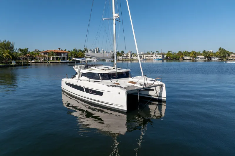 Slide: The Image of 2025 Fountaine Pajot FP41 Catamaran on calm water, with waterfront homes in the background. - 6