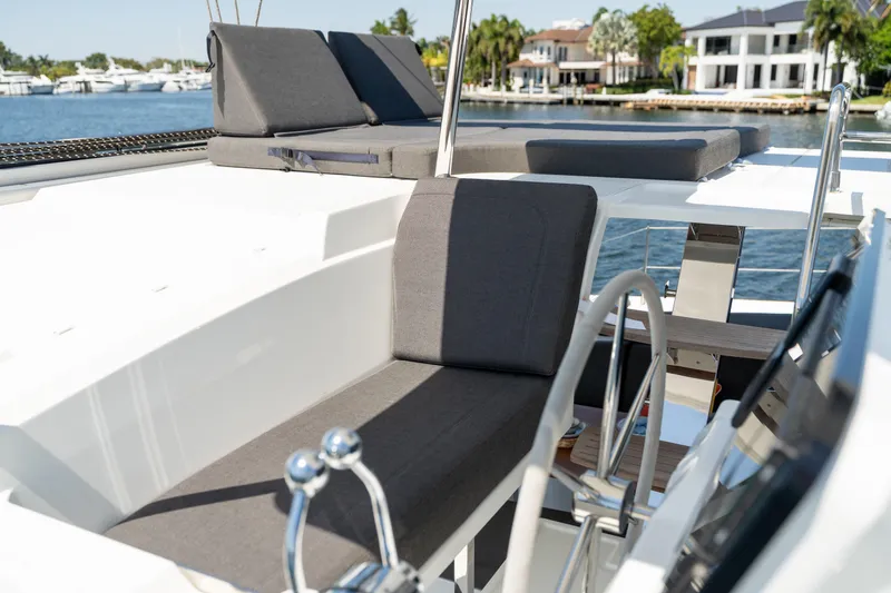 Slide: The Image of 2025 Fountaine Pajot FP41 Catamaran deck with seating and steering wheel, docked by waterfront homes. - 65