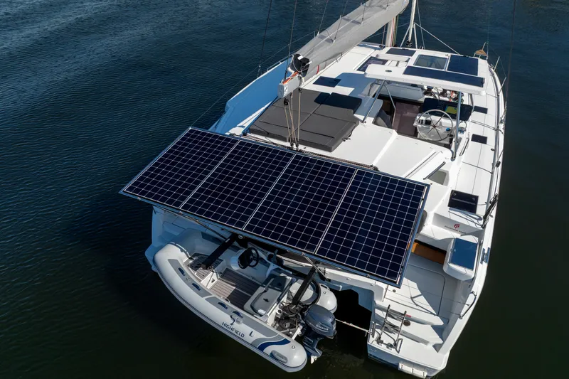 Slide: The Image of 2025 Fountaine Pajot FP41 Catamaran with solar panels and dinghy on calm water. - 8