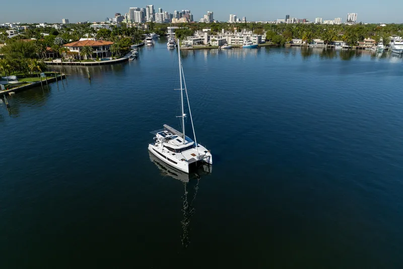 Slide: The Image of 2025 Fountaine Pajot FP41 Catamaran sailing in a serene waterfront cityscape. - 9