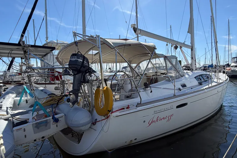 Slide: The Image of Beneteau 43 sailboat from 2008 docked in a marina, featuring a dinghy and outboard motor. - 3