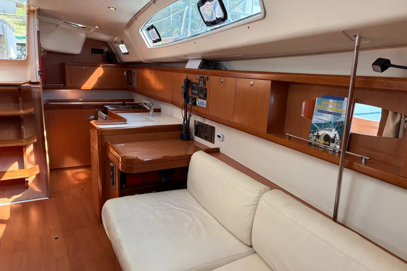 Slide: The Image of Interior of a 2008 Beneteau 43 sailboat with wooden cabinetry and white seating. - 38