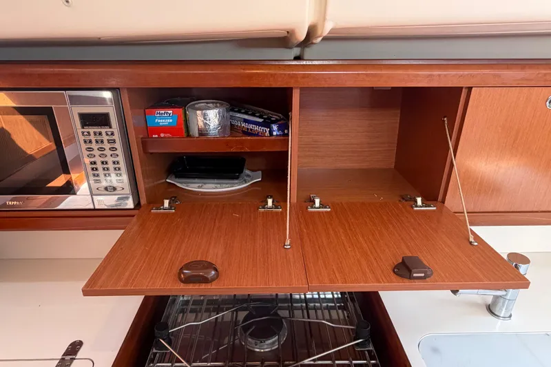 Slide: The Image of Galley of 2008 Beneteau 43 yacht with microwave and open wooden cabinets. - 50