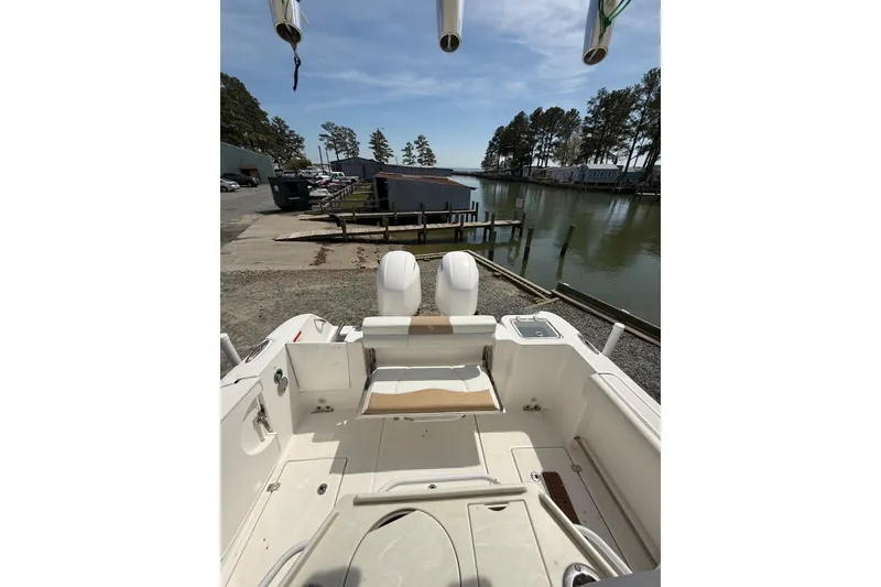 Slide: The Image of 2019 Edgewater 262CC boat interior with seating and storage, docked near a serene waterfront. - 14