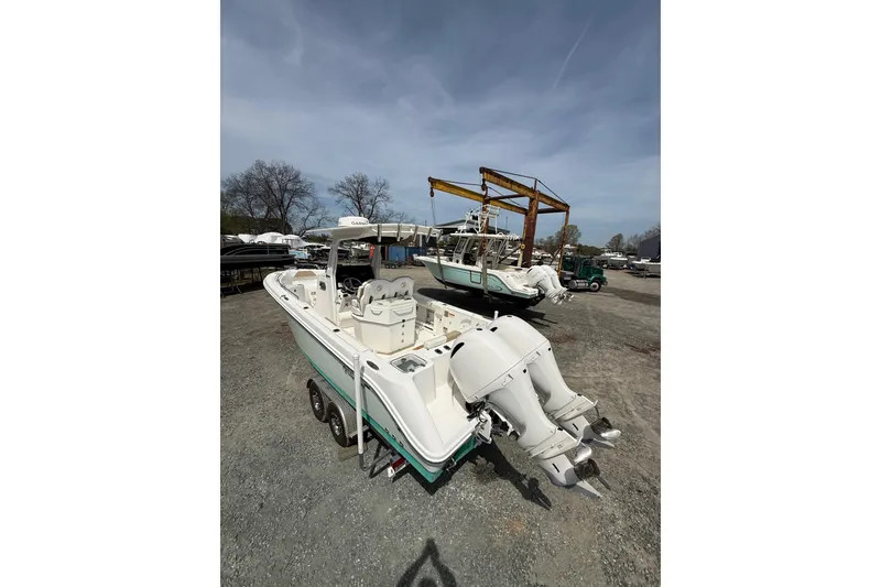 Slide: The Image of 2019 Edgewater 262CC boat with dual engines docked by a serene waterfront. - 18