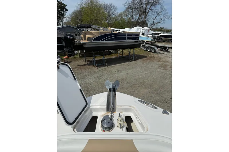 Slide: The Image of 2019 Edgewater 262CC boat on trailer, parked outdoors among trees and other boats. - 2