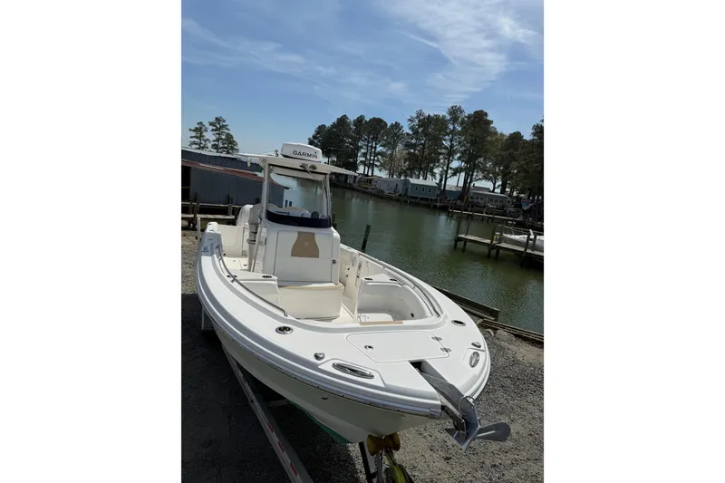 Slide: The Image of 2019 Edgewater 262CC boat interior with seating and console, parked outdoors. - 20