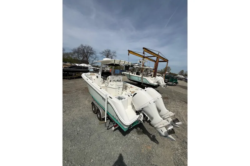 Slide: The Image of 2019 Edgewater 262CC boat on trailer at marina, surrounded by trees and equipment. - 22