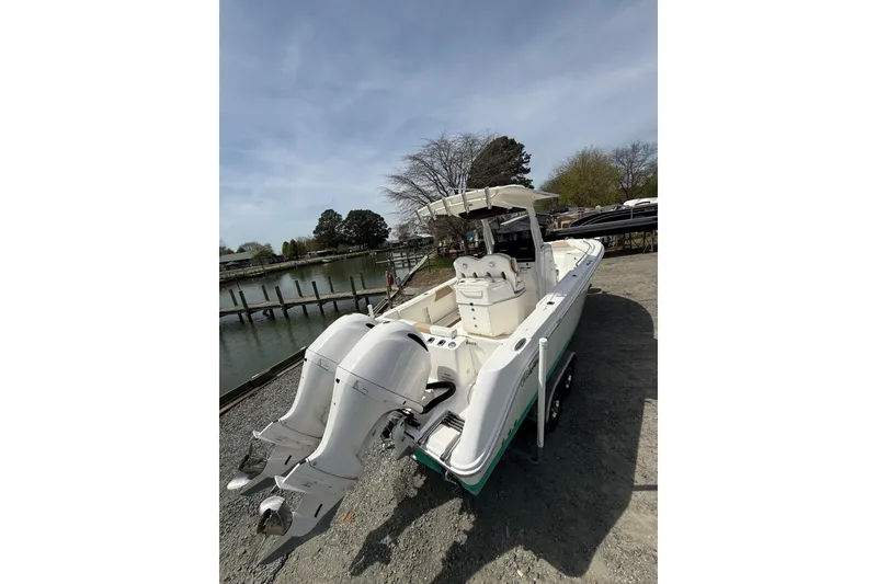 Slide: The Image of 2019 Edgewater 262CC boat docked by a serene waterfront with trees in the background. - 23