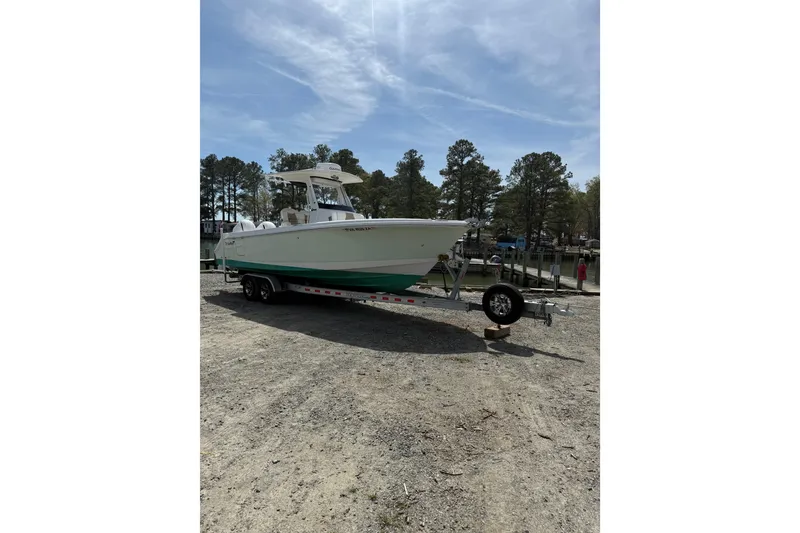 Slide: The Image of 2019 Edgewater 262CC boat with dual engines on a trailer, parked outdoors. - 25