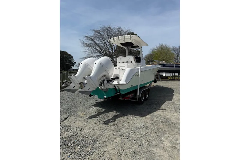 Slide: The Image of 2019 Edgewater 262CC boat on trailer by waterfront, clear sky background. - 27