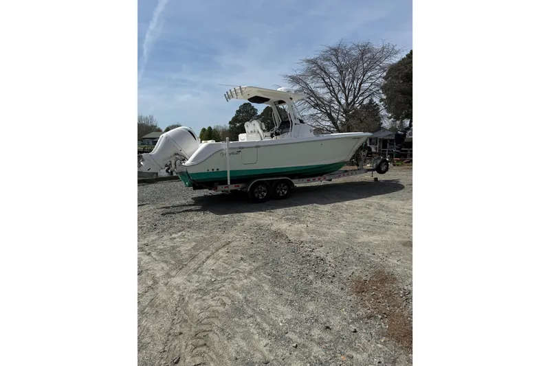 Slide: The Image of 2019 Edgewater 262CC boat on trailer, parked outdoors near a marina. - 28