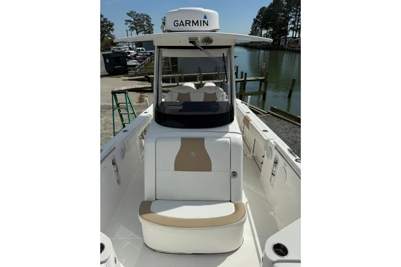 Slide: The Image of 2019 Edgewater 262CC boat interior with center console and seating, parked outdoors. - 3