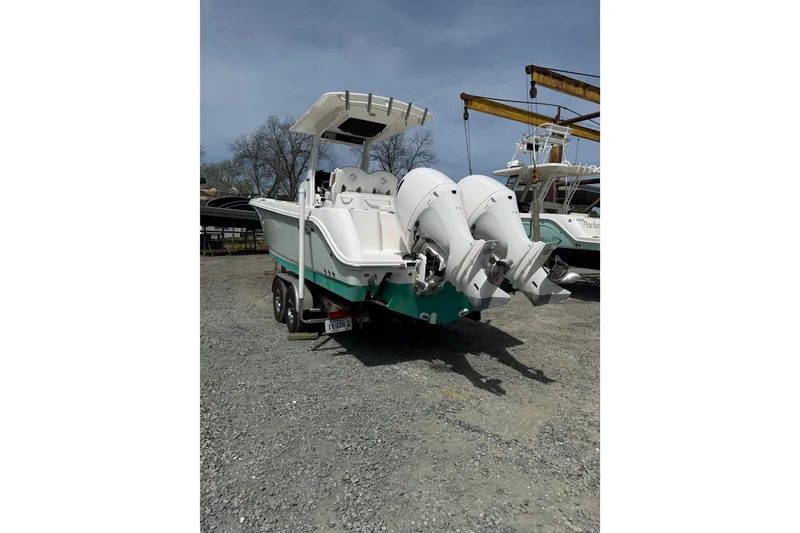 Slide: The Image of 2019 Edgewater 262CC boat with dual outboard motors on a trailer, parked outdoors. - 30