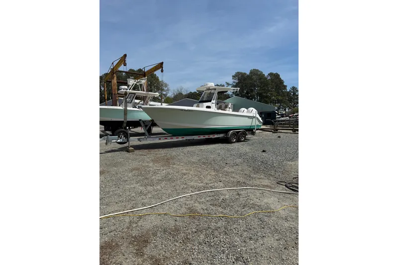 Slide: The Image of 2019 Edgewater 262CC boat on trailer, parked near waterfront under clear blue sky. - 32