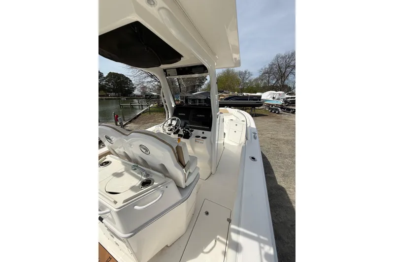 Slide: The Image of 2019 Edgewater 262CC boat interior with helm, seating, and storage, dockside view. - 34