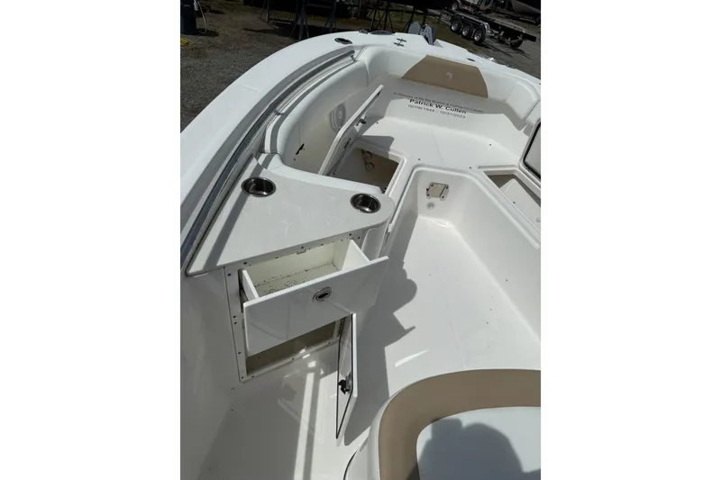 Slide: The Image of 2019 Edgewater 262CC boat with open anchor compartment, parked near other boats. - 5
