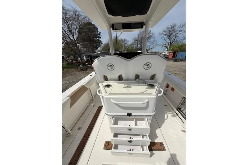 Slide: The Image of 2019 Edgewater 262CC boat interior with open storage compartments, parked outdoors. - 9