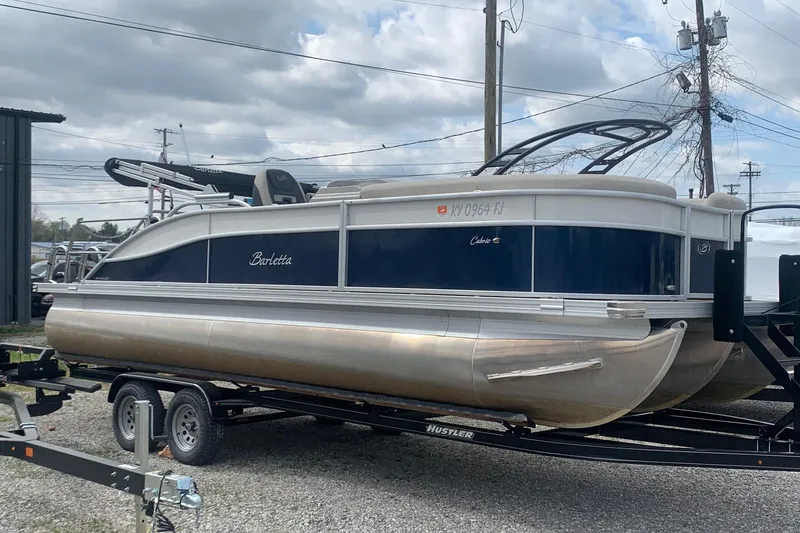 The Image of 2022 Barletta C22UC pontoon boat on trailer, parked outdoors under cloudy sky. - 0