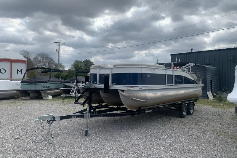 Slide: The Image of 2022 Barletta C22UC pontoon boat on trailer under cloudy sky. - 2