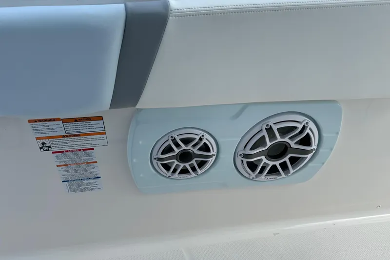 Slide: The Image of 2025 Robalo R360 Center Console boat speakers and warning labels on white interior. - 8