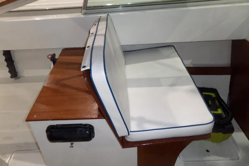 Slide: The Image of 1980 Lyman-Morse Fisherman Sleeper boat seat with white cushion and wooden base. - 16