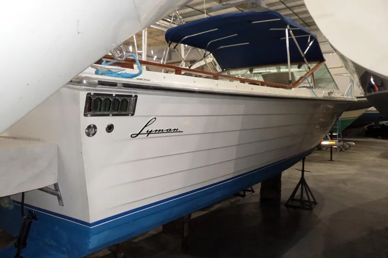 Slide: The Image of 1980 Lyman-Morse Fisherman Sleeper boat in storage, featuring a sleek white and blue design. - 4