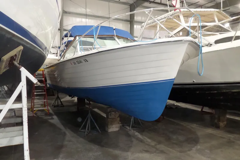 The Image of 1980 Lyman-Morse Fisherman Sleeper boat in storage, featuring a blue and white hull. - 1