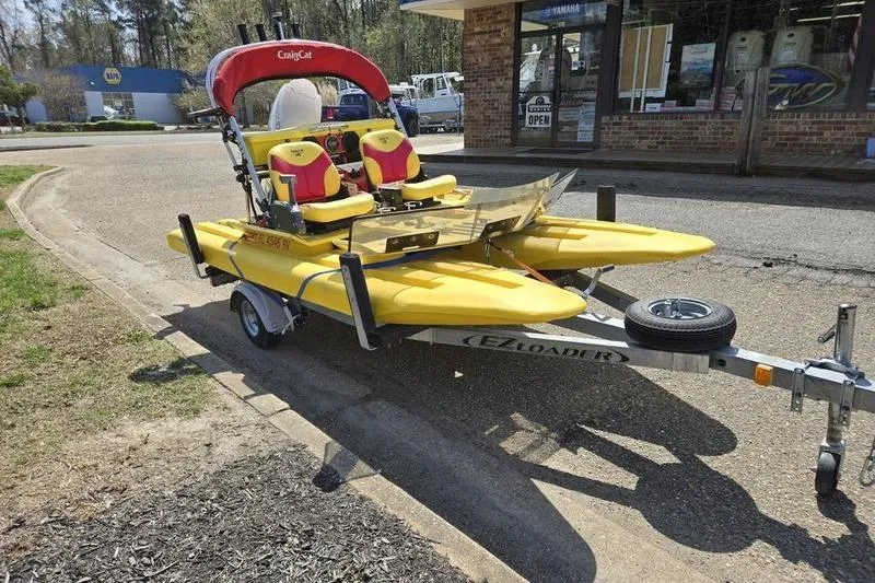 Slide: The Image of Yellow 2019 CraigCat CATCHIT boat on trailer, parked near a store. - 5