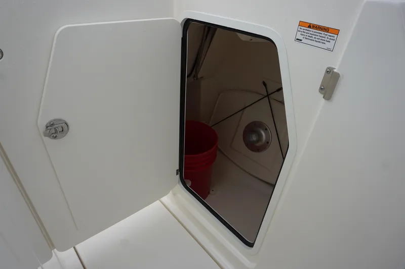 Slide: The Image of Open storage compartment on 2026 Boston Whaler 240 Vantage boat, featuring a red bucket inside. - 29