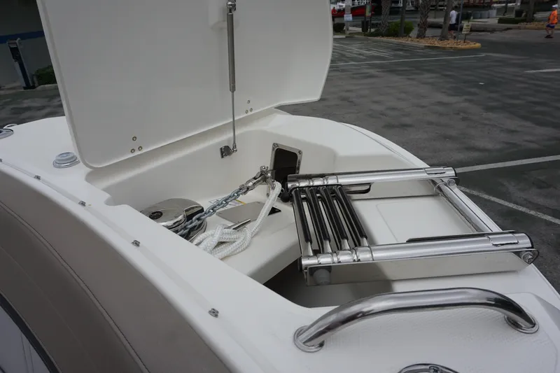 Slide: The Image of 2026 Boston Whaler 240 Vantage boat anchor storage with ladder in open compartment. - 36