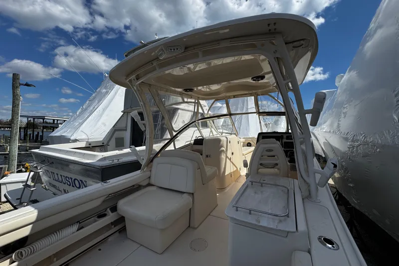 Slide: The Image of 2019 Grady-White Freedom 275 boat interior with seating and helm, docked under a blue sky. - 19