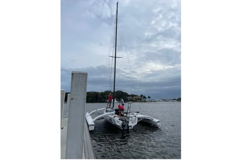 Slide: The Image of 2021 Corsair 880 Sport trimaran docked on a cloudy day, with people onboard. - 3