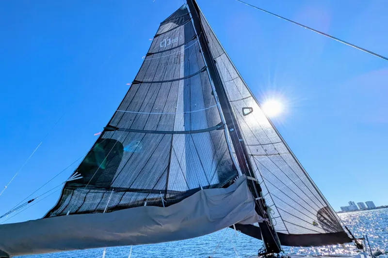 Slide: The Image of Sailing on a 2021 Corsair 880 Sport with sunlit sails against a clear blue sky. - 5