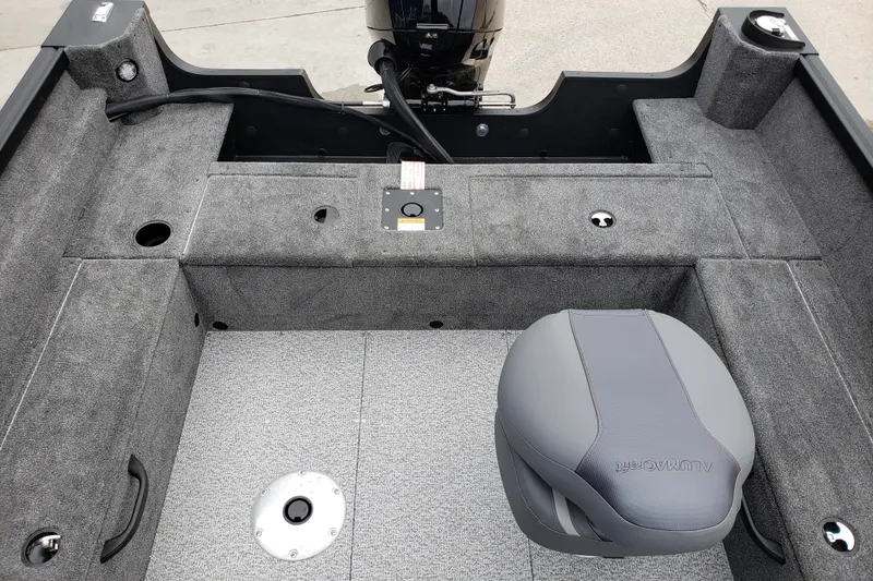 Slide: The Image of 2026 Alumacraft Voyageur 175 SC boat interior with gray seating and carpeted flooring. - 16